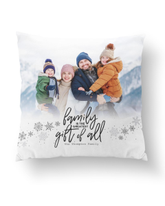 White personalized pillow featuring a winter family photo of four in warm coats with the phrase 'Family is the Greatest Gift of All' and snowflake accents.